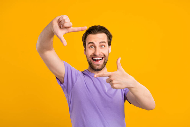 Photo of crazy excited guy make frame gesture take shot photo wear purple t-shirt isolated yellow color background - Φωτογραφία, εικόνα