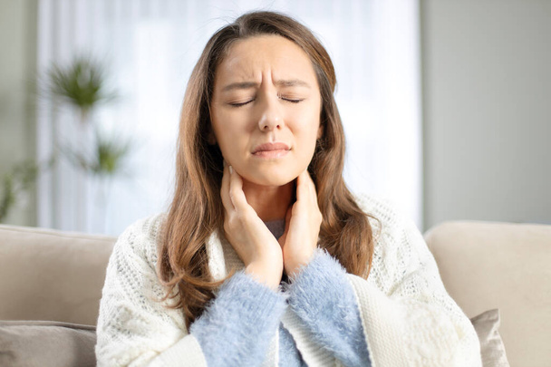 Jonge vrouw raakt pijnlijke nek, keelpijn tegen griep, verkoudheid en infectie - Foto, afbeelding