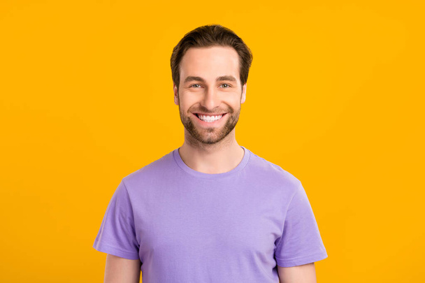Photo of positive handsome guy look camera toothy beaming smile wear purple t-shirt isolated yellow color background - Zdjęcie, obraz