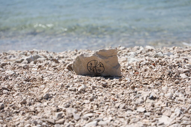 Stone with pictogram from numbers on the beach - Photo, Image