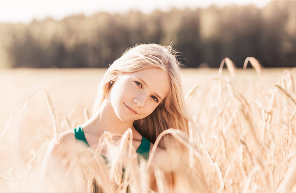 Krásná dospívající dívka s dlouhými bílými vlasy procházející pšeničné pole na slunný den - Fotografie, Obrázek