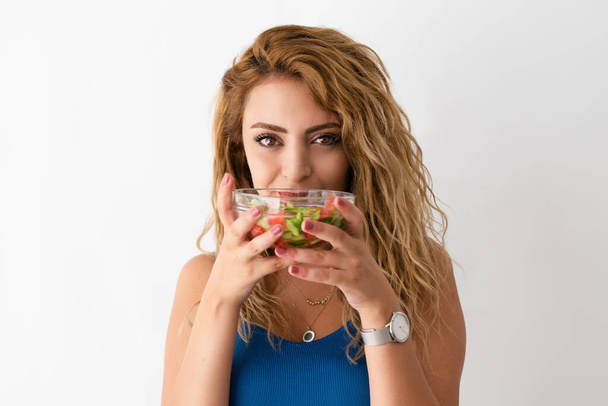 Young beautiful woman is eating salad for a fit body and healthy life. - Foto, afbeelding