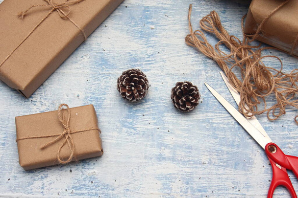 gift wrapping from Kraft paper wrapped with twine, the concept of handmade, light blue tabletop. - Foto, Imagen