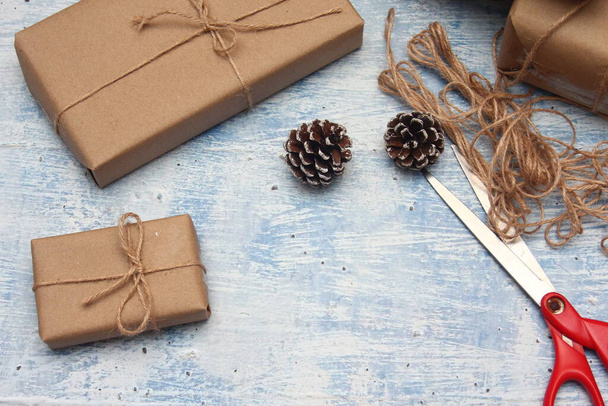 gift wrapping from Kraft paper wrapped with twine, the concept of handmade, light blue tabletop. - Valokuva, kuva