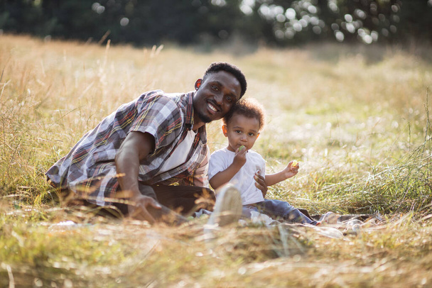 Африканський батько приймає маленького сина під час пікніка про природу. - Фото, зображення