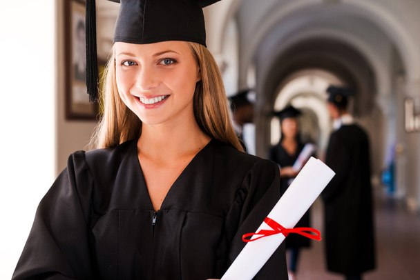 Woman in graduation gown holding diploma - 写真・画像