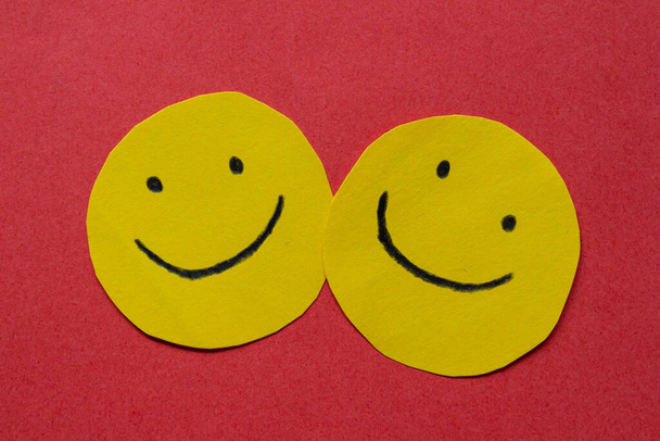 Τα χαρούμενα πρόσωπα ζωγραφισμένα στο αυτοκόλλητο. Ευτυχία, αγάπη και φιλία. Χαμογελαστά πρόσωπα σε κίτρινο χαρτί. - Φωτογραφία, εικόνα