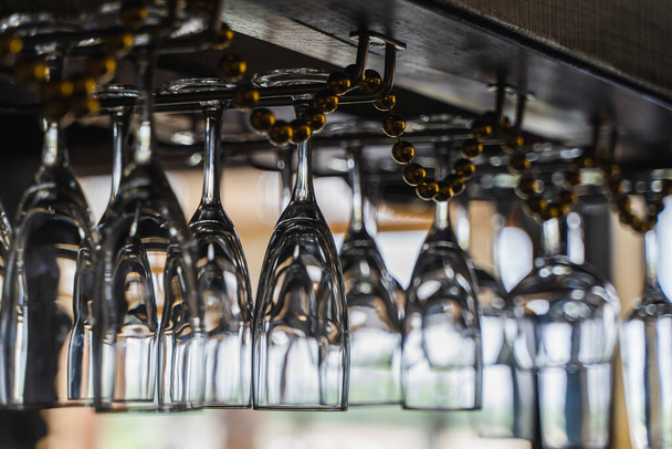 Luxury wine and champagne glasses hanging up side down over the bar counter. - Fotó, kép