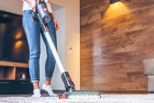 Woman cleaning floor and carpet with cordless vacuum cleaner at home - Foto, Imagem