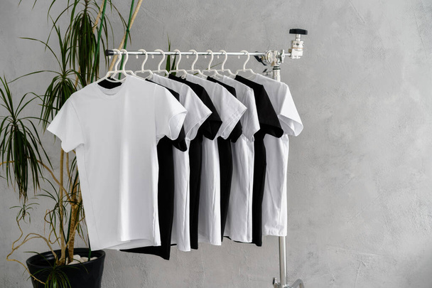 Row of black and white t-shirts hanging on rack - Fotó, kép