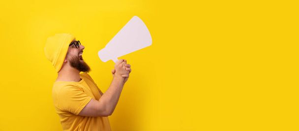 hombre gritando en megáfono sobre fondo amarillo, diseño panorámico - Foto, Imagen