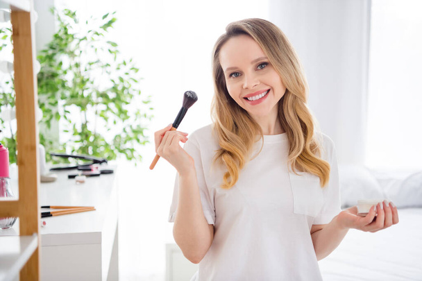 Photo portrait young woman in white outfit doing make up keeping powder brush - Fotografie, Obrázek