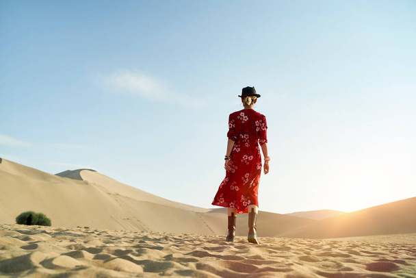 πίσω όψη μιας Ασιάτισσας που περπατάει στην έρημο κάτω από τον γαλάζιο ουρανό - Φωτογραφία, εικόνα