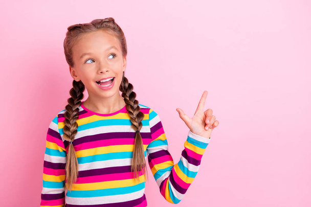 Photo of little lady indicate forefinger empty space look up wear striped shirt isolated pink color background - 写真・画像
