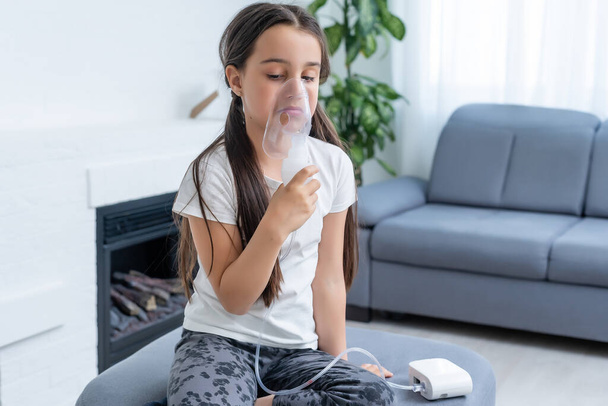 Little girl making inhalation with nebulizer at home. child asthma inhaler inhalation nebulizer steam sick cough concept. - Foto, afbeelding