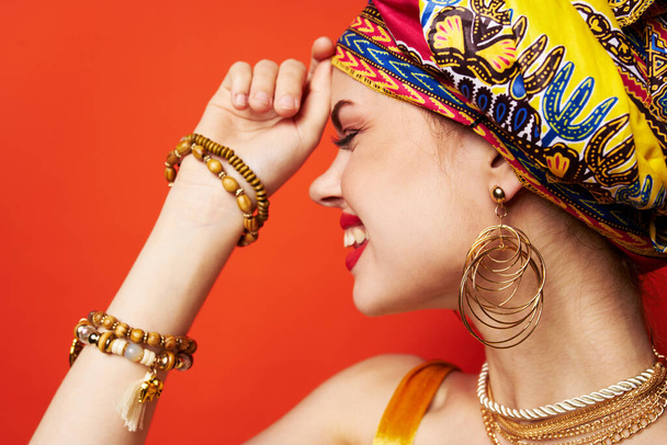 mooie vrouw in veelkleurige tulband aantrekkelijke look sieraden geïsoleerde achtergrond - Foto, afbeelding