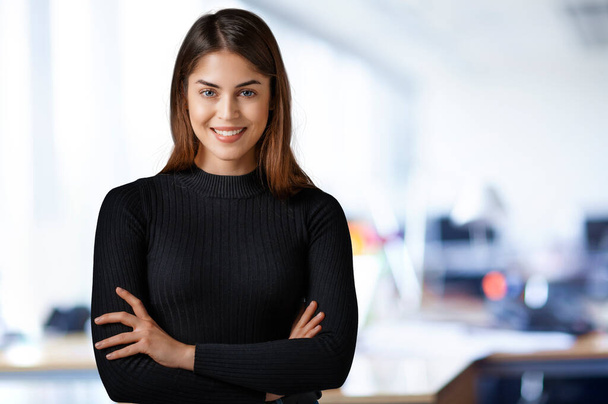Portrait shot of young businesswoman looking at camera and smiling while standing at the office. Copy space.  - Foto, immagini