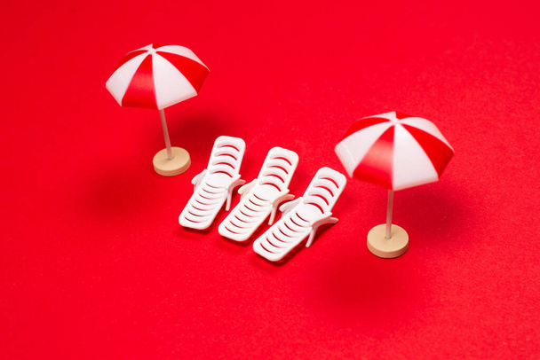 Due lettini e ombrelloni rossi su sfondo rosso. Copia spazio. - Foto, immagini