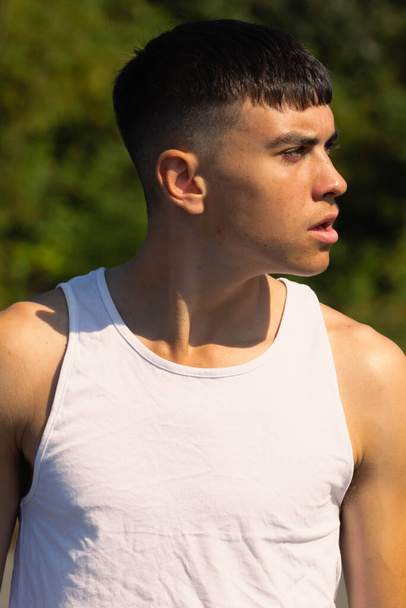 An 18 year old teen boy in a sleeveless top on a late summer's day - Фото, изображение