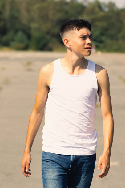 An 18 year old teen boy in a sleeveless top on a late summer's day - Photo, Image