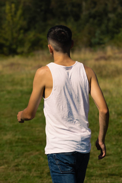 An 18 year old teen boy in a sleeveless top on a late summer's day - Φωτογραφία, εικόνα