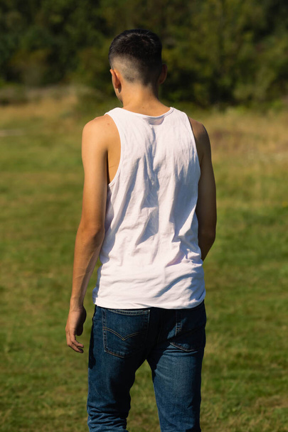 An 18 year old teen boy in a sleeveless top on a late summer's day - Valokuva, kuva