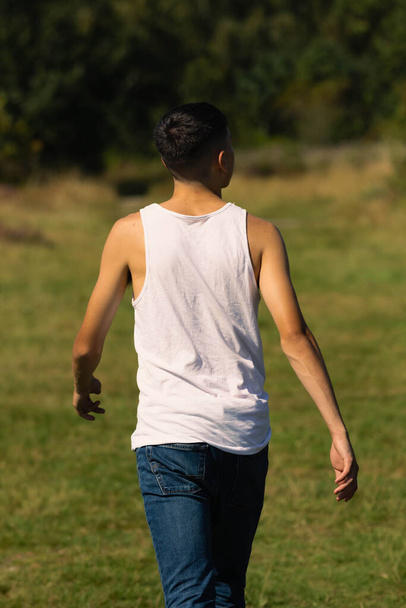 An 18 year old teen boy in a sleeveless top on a late summer's day - Φωτογραφία, εικόνα