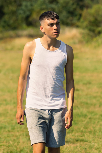 An 18 year old teen boy in a sleeveless top on a late summer's day - Valokuva, kuva