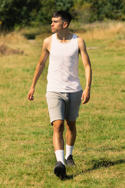 An 18 year old teen boy in a sleeveless top on a late summer's day - 写真・画像