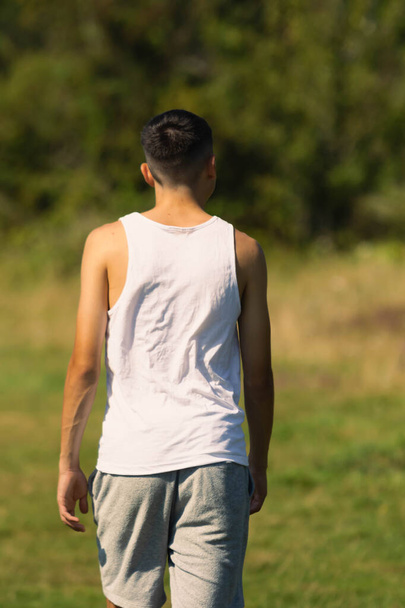 An 18 year old teen boy in a sleeveless top on a late summer's day - Photo, image