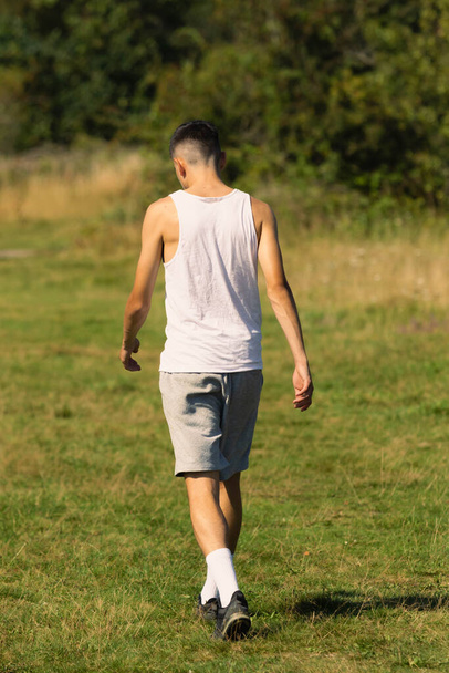 An 18 year old teen boy in a sleeveless top on a late summer's day - Photo, Image