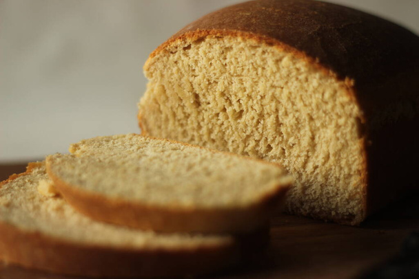 Кусочки домашнего хлеба из пшеницы, хранящиеся на деревянной доске. - Фото, изображение