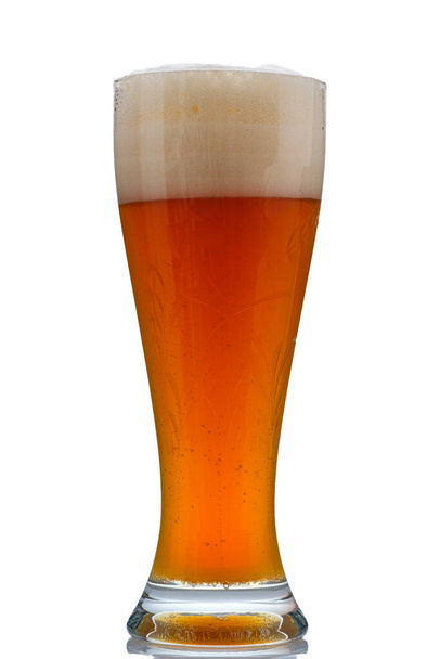 A vertical shot of a wheat beer with foam in a glass isolated on white - Foto, Bild