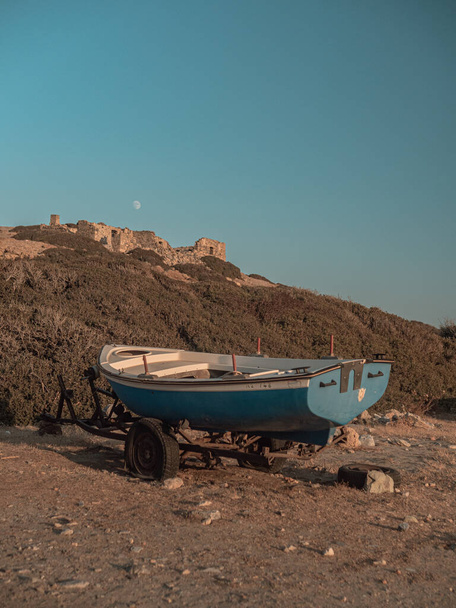 A vertical shot of a blue boat on a barrow in the seashore - Fotó, kép