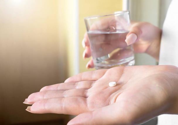 close up hand woman taking pill take a medicine in hand holding a cup glass of drinking water. - Photo, image