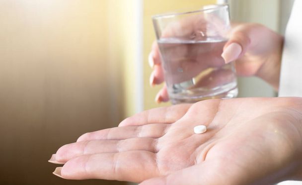 close up hand woman taking pill take a medicine in hand holding a cup glass of drinking water. - 写真・画像