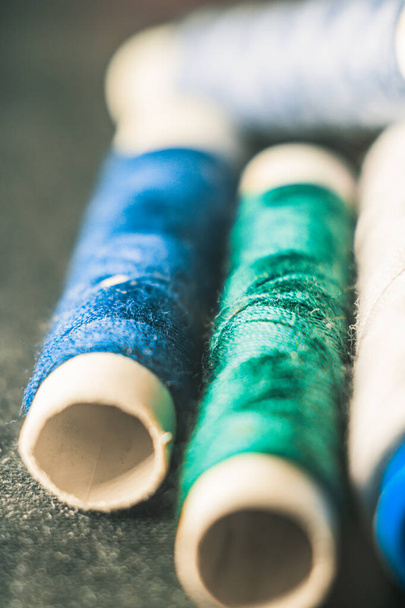A vertical shot of spools of blue and green threads - Фото, зображення