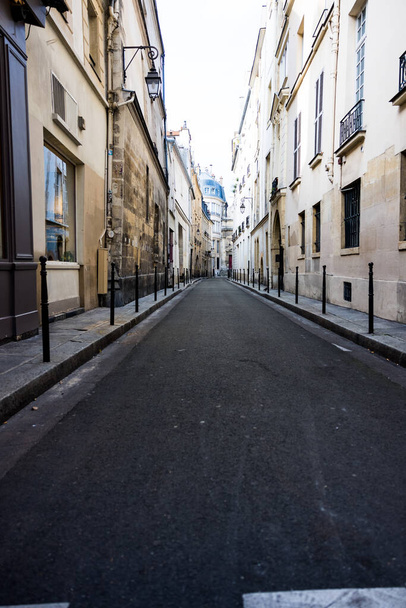 A vertical shot of a small road alleyway through buildings in Paris, France - Photo, Image