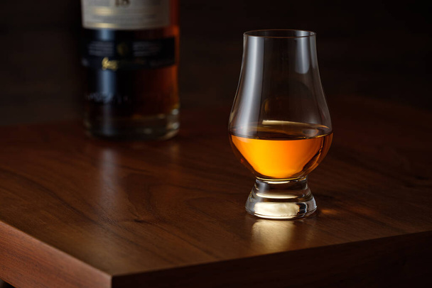 A luxurious whiskey on a wooden brown table with bottle - Фото, изображение