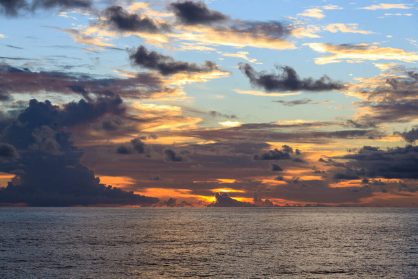 sunset on open ocean against the backdrop of clouds with the sun's rays breaking through - Foto, Imagem