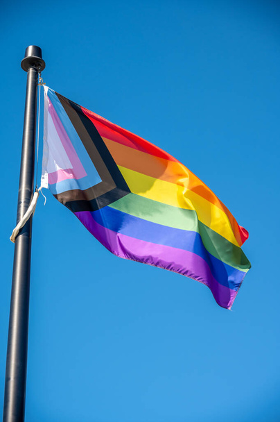 A close up of Rainbow LGBT flag fluttering on blue sky background - Foto, Bild