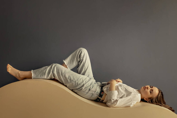 Портрет молодой женщины, лежащей на геометрическом песчаном диване. - Фото, изображение