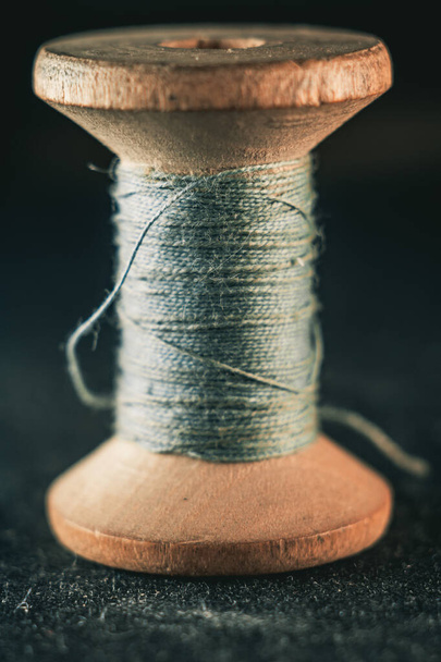 A vertical shot of a spool of blue thread - 写真・画像
