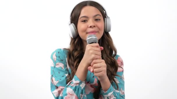 alegre adolescente chica en auriculares con micrófono hablar con cámara de entrevista o canto, tecnología - Metraje, vídeo