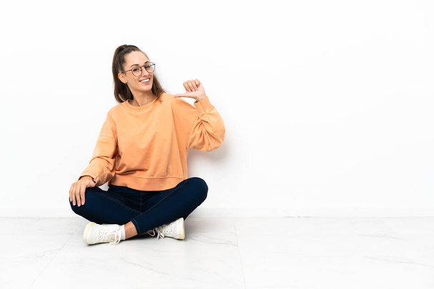 Young woman sitting on the floor proud and self-satisfied - Photo, Image