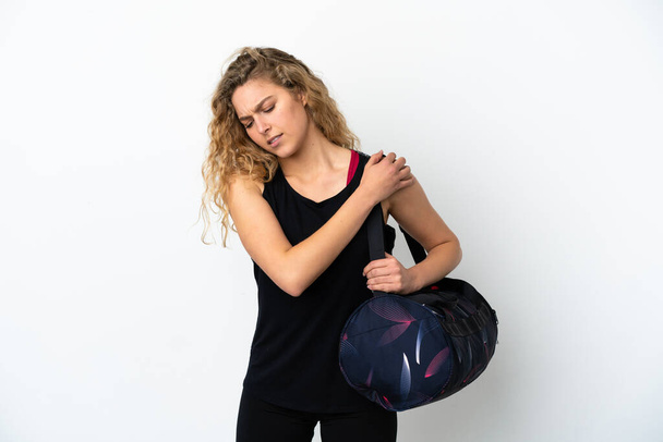 Young sport woman with sport bag isolated on white background suffering from pain in shoulder for having made an effort - Fotó, kép