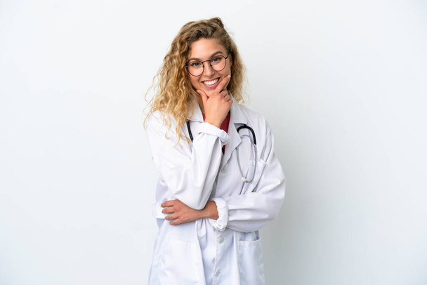 Νεαρή γιατρός ξανθιά γυναίκα απομονωμένη σε λευκό φόντο χαρούμενη και χαμογελαστή - Φωτογραφία, εικόνα