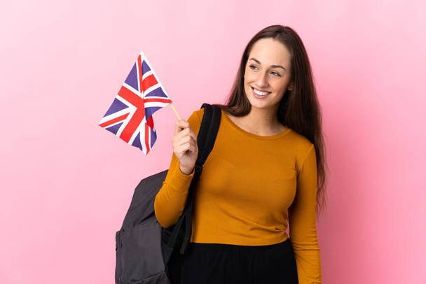 Junge hispanische Frau mit einer britischen Flagge, die zur Seite schaut und lächelt - Foto, Bild