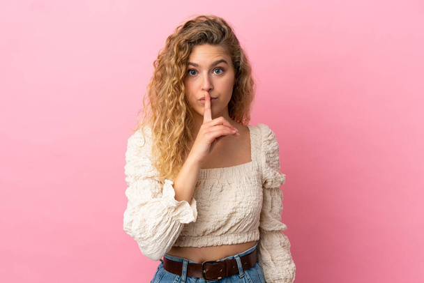 Young blonde woman isolated on pink background showing a sign of silence gesture putting finger in mouth - Фото, зображення