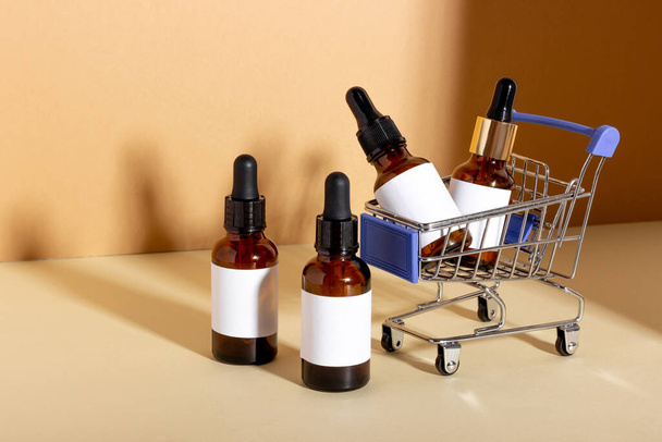A set of cosmetic products with a dropper for facial skin care in a shopping trolley - Fotografie, Obrázek